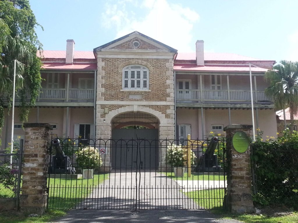 The historic Barbados Museum building at Garrison Savannah with a gated entrance and lush garden