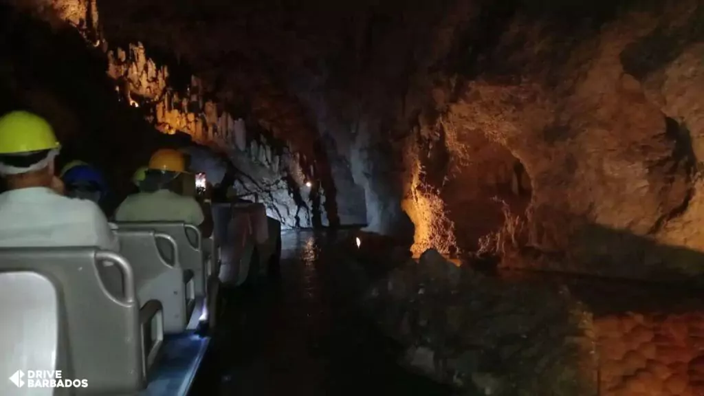 Visitors on a tram tour exploring the illuminated underground passageways of Harrison's Cave in Barbados