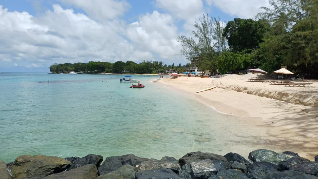 Holetown Beach – West Coast St. James Barbados Holetown Beach in Saint James, Barbados, with clear waters, boats, and shaded sunbeds.