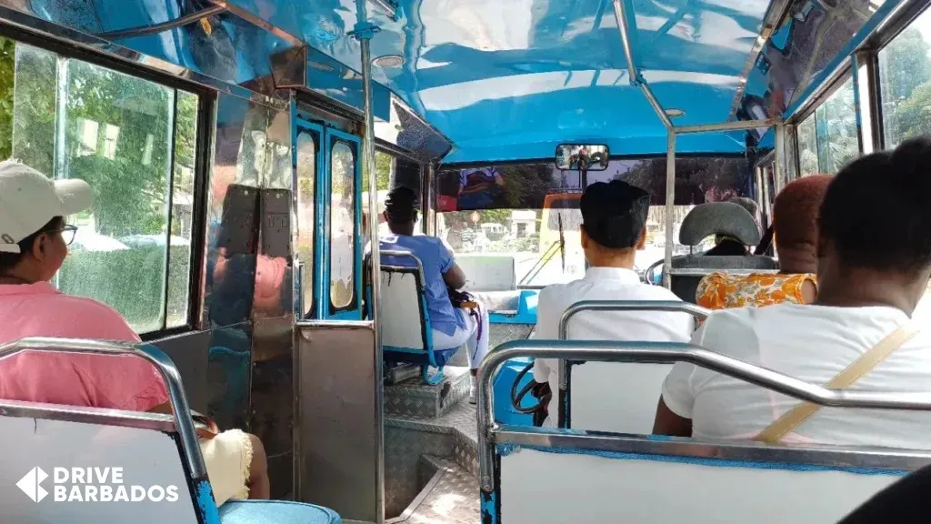 Interior view of a yellow mini bus in Barbados, showcasing passengers during a typical ride.